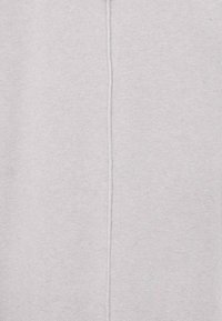 Tessuto di cotone grigio chiaro con una superficie testurizzata, caratterizzato da una cucitura centrale che corre verticalmente lungo il mezzo.
