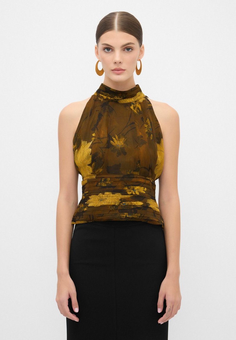 Top halter floral marrón hecho de un tejido transparente y texturizado con detalles de fruncido, acompañado de una falda negra ajustada. Aretes circulares grandes.