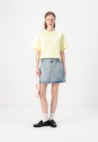 Ανοιχτό κίτρινο cropped t-shirt, τζιν φούστα με ξεθωριασμένο σχέδιο, μαύρα παπούτσια, λευκές κάλτσες και �μια μικρή ροζ τσάντα. Απλός, καθημερινός σχεδιασμός.