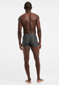 Herren Badehose in Dunkelgrau, aus glattem Stoff gefertigt, mit figurbetontem Design und minimalistischer Optik, ausgestattet mit einem mittelhohen Bund.