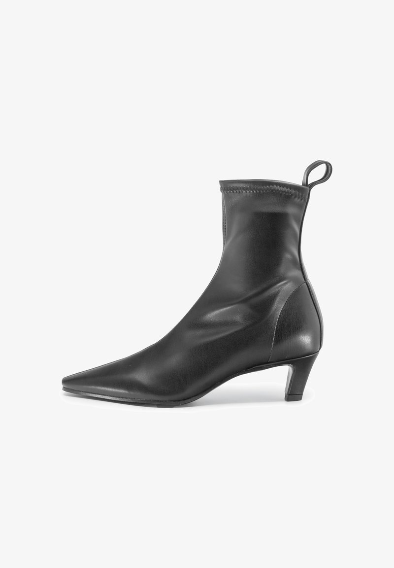 Stivali neri in pelle alla caviglia con punta appuntita, tacco sottile e apertura elasticizzata. Texture liscia con minimi dettagli e un tirante.