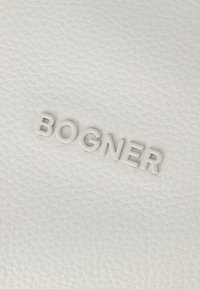 Sfondo in pelle bianca con logo "BOGNER" in rilievo di colore abbinato, caratterizzato da una superficie liscia e texture.