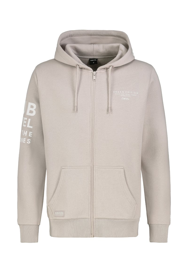 Hellbeige Zip-up Hoodie aus weichem Stoff, mit Kapuze und Zugband, zwei Vordertaschen und weißem Drucktext am linken Ärmel.