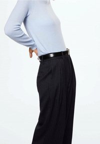 Pull ajusté à manches longues bleu clair associé à un pantalon noir fluide à fines rayures, complété par une ceinture en cuir noir avec une boucle argentée.