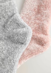 Luksus strømper i lysegrå og blød pink, lavet af fuzzy, tekstureret materiale med subtil glimmer. Har runde tæer og et hyggeligt design.