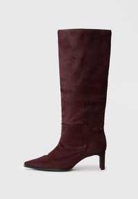 Botte à talon haut bourgogne avec un bout pointu, fabriquée en matériau texturé, présentant un tige haute et un talon fin, finie avec un bord lisse.