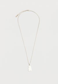 Ασημένιο κολιέ με αλυσίδα και μικρό μενταγιόν σε σχήμα λευκής καραμέλας αρκουδάκι σε λευκό φόντο.