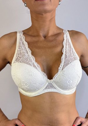 Sostenedor de encaje en color off-white con un escote en V profundo, patrón floral, tirantes anchos y bordes festoneados. Copas suaves y estructuradas para mayor soporte.