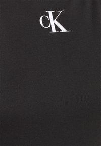 Tissu noir avec un petit logo blanc "cK" imprimé près du centre supérieur.