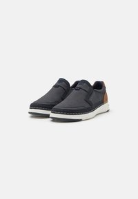 Slip-on sko med en teksturert mørkegrå stoffoverdel, brune skinndetaljer og hvite gummisåler. Har kontrasterende sømmer for ekstra detaljer.
