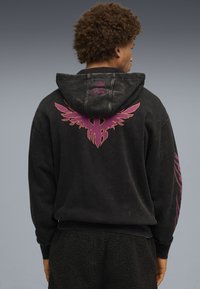 Czarna bluza z kapturem wykonana z miękkiej tkaniny, z dużym fioletowym wizerunkiem orła na plecach oraz różowymi akcentami na rękawach.