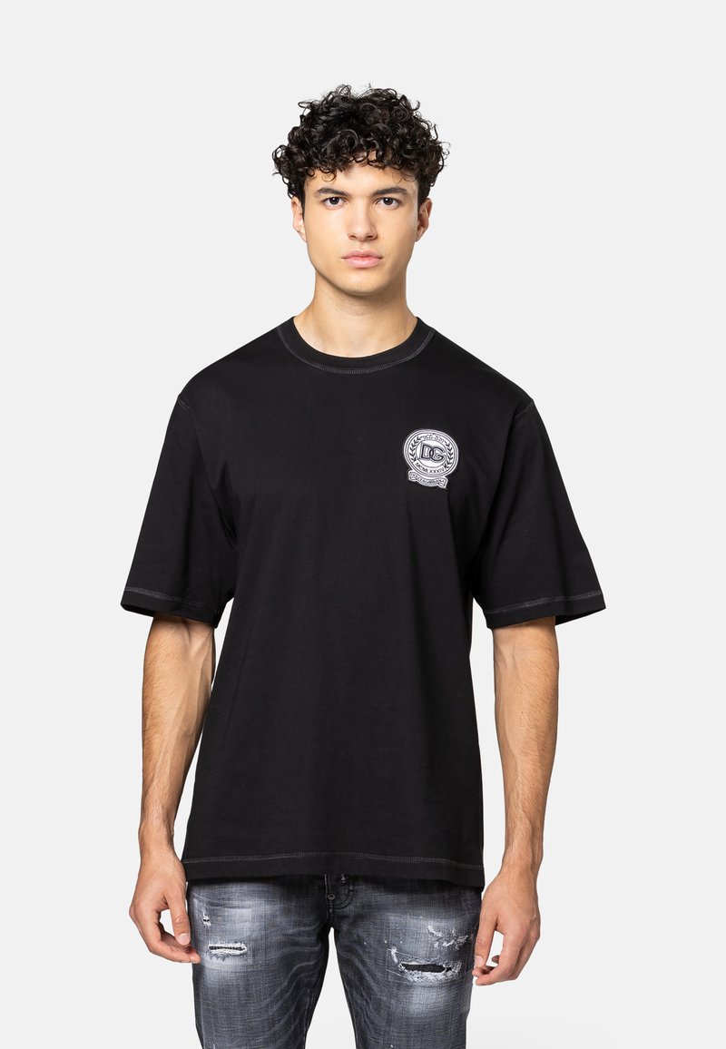 Zwarte katoenen t-shirt met een ronde halslijn en korte mouwen, met een witte logopatch op de linkerkant van de borst en contrasterende stikdetails.