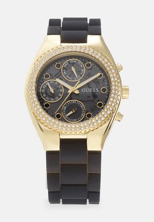 Svart silikonrem klokke med gullfarget klokkehus, svart urskive, gullakenter og krystallbesatt bezel. Funksjoner inkluderer flere sub-dials.