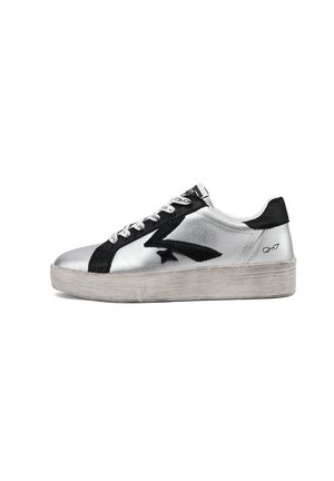 Sneaker argento basso con design a stella nera e fulmine, lacci bianchi, linguetta posteriore nera e suola spessa in gomma usurata.