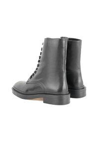 Bottes de cheville en cuir noir avec une finition lisse, un bout rond et une semelle robuste à profil bas. Elles présentent un design à lacets avec neuf œillets.