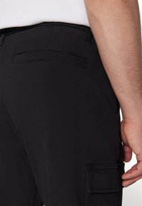 Svarta cargo-byxor med en mjuk bomullsduk, sidofickor och en elegant design med minimal sömnad på baksidan.