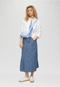 Lichtblauwe gewatteerde schoudertas met gevlochten band, gecombineerd met een witte denimjas, gestreept T-shirt en een denimrok. Witte sneakers.