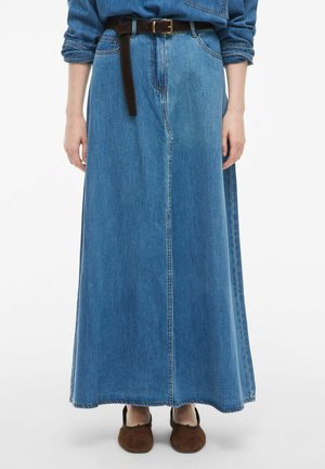 Jupe maxi en denim bleu moyen avec une coupe droite. Elle est dotée d'une ceinture en cuir marron et d'un ourlet légèrement effiloché. Chaussures : mocassins marron.