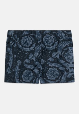 Bañadores de color azul marino con un estampado floral en tonos azules. Cintura elástica con "VERSACE" impreso en el lateral. Textura suave.