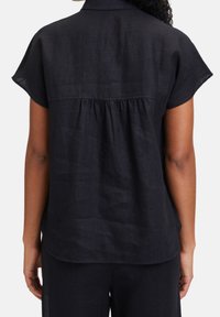 Camicia in lino nero con maniche corte, dettaglio di piega sul retro e orlo morbido e arrotondato. Tessuto liscio e design leggero.