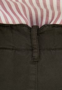 Tessuto a righe di cotone in rosa chiaro e crema abbinato a pantaloni di cotone verde oliva scuro, con passanti per cintura e dettagli cuciti.