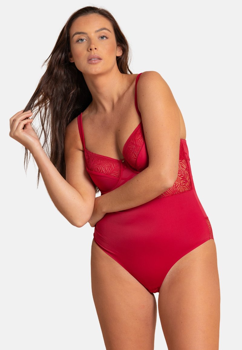 Bodysuit rouge en tissu lisse avec des détails en dentelle au niveau de la poitrine, des bretelles ajustables et un design de jambes échancrées.