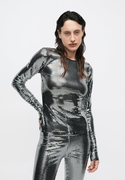 Sudraba metālisks krekls ar garām piedurknēm un atbilstošas bikses ar teksturētu, fliterēm rotātu dizainu, pieguļošu siluetu un garām piedurknēm.