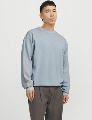 Lichtblauwe sweatshirt in een relaxte pasvorm, met lange mouwen, geribde manchetten en een ronde hals, gecombineerd met grijze broek.
