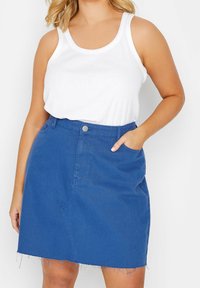 Modrá denimová sukně s roztrhaným lemem, přední kapsou a přiléhavým pasem se stříbrným knoflíkem. Nosená s bílým tílkem.