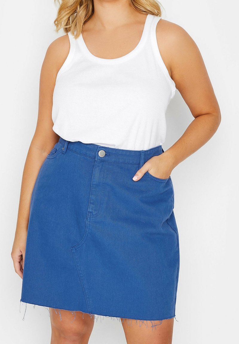 Modrá denimová sukně s roztrhaným lemem, přední kapsou a přiléhavým pasem se stříbrným knoflíkem. Nosená s bílým tílkem.