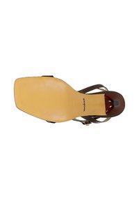 Sandalette mit quadratischer beiger Sohle und dunkelbraunen Riemen und Ferse, von unten gesehen, zeigt den Markennamen "Wojas" nahe der Ferse.
