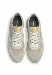 Scarpe da ginnastica in suede grigio chiaro e beige con lacci crema, punta rotonda, colletto imbottito e una piccola etichetta di brand sulla linguetta.