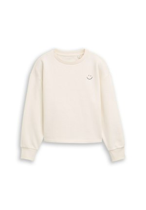 Cremfarbener, verkürzter Sweatshirt aus weicher Baumwolle, mit langen Ärmeln und einem kleinen schwarzen Smiley-Emblem auf der linken Brust.