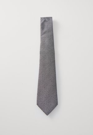 Grijze stropdas van een gestructureerde stof, met een subtiel patroon. De vorm is smal, loopt taps toe naar een puntige punt, met een logo aan de bovenkant.