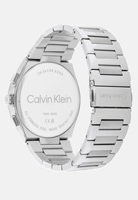 Orologio da polso in acciaio inossidabile con bracciale in metallo argentato, cassa rotonda e retro inciso con il logo Calvin Klein. Impermeabile fino a 3 bar.