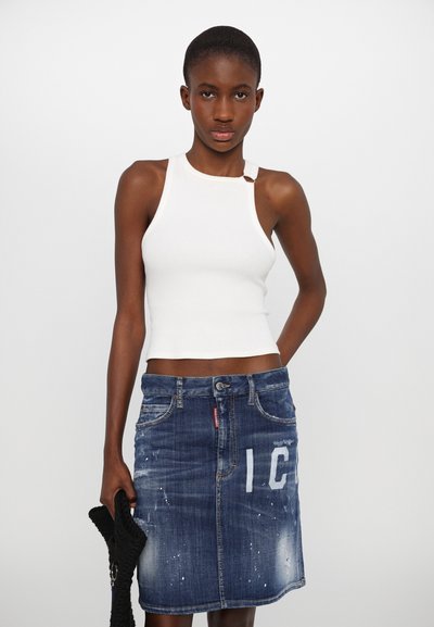Weißes geripptes Tanktop mit Schulterträger-Detail, kombiniert mit einem blauen Jeansrock mit abgewetzten Akzenten und weißer Aufschrift "IC."