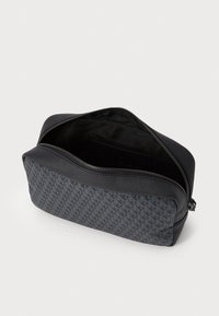 Bolso de cosméticos negro con una superficie texturizada, que presenta un patrón sutil. Cierre de cremallera y interior forrado, mostrando un diseño espacioso.