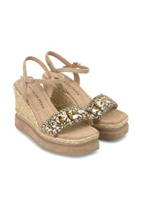 Sandalias de cuña color beige con una correa de tela texturizada, adornadas con strass dorados y claros, con una correa ajustable en el tobillo.