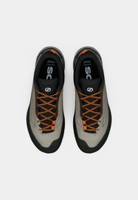 Gray athletic shoes with black accents, featuring orange laces and a textured surface, designed for performance and durability.