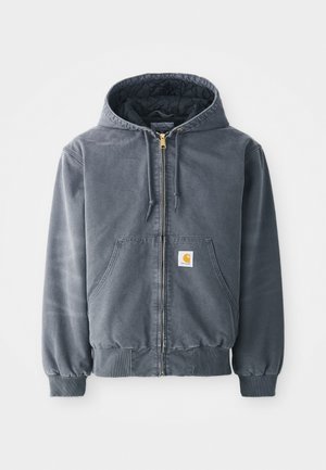 Felpa grigia con cappuccio e zip frontale, due grandi tasche, polsini a coste e un patch con logo sulla tasca sinistra. Realizzata in tessuto resistente.