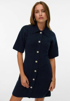 Vestido de punto azul marino con mangas cortas, cuello tipo solapa y grandes botones beige en la parte frontal; textura suave y ajuste entallado.