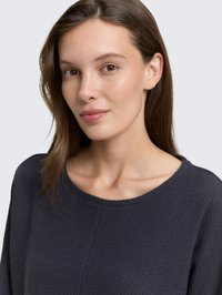Navy textured top with a round neckline and long sleeves, featuring ribbed detailing and a relaxed fit. Smooth fabric adds depth.