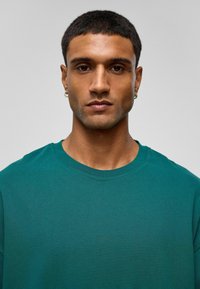 Teal kortlijst t-shirt met een ronde hals. Gemaakt van zachte stof, met een subtiele textuur en een relaxte pasvorm.