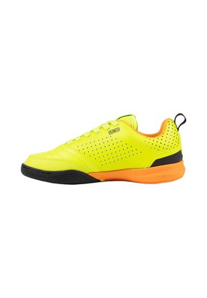 Zapato deportivo amarillo brillante con suela naranja, parte delantera de la suela negra, lateral perforado y lengüeta en el talón mirando hacia la derecha.