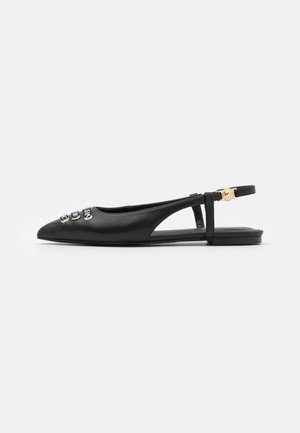 Czarny, spiczasty, płaski pantofel typu slingback z trzema złotymi i czarnymi ozdobnymi guzikami na przodzie oraz złotą klamrą na pasku wokół kostki.