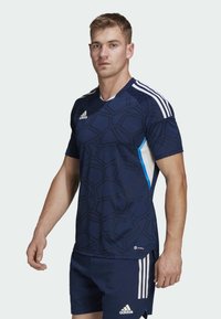 Marineblaues Fußballtrikot mit geometrischem Muster, kurzen Ärmeln und weißen Adidas-Streifen. Hergestellt aus leichtem Stoff, mit Rundhalsausschnitt.