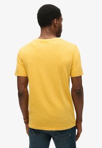 T-shirt a maniche corte, con scollo rotondo, di un giallo brillante, realizzata in tessuto testurizzato, con una vestibilità rilassata e dettagli di cucitura sottili.