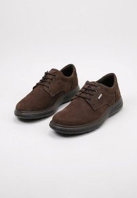 Chaussures à lacets en suède marron avec un bout arrondi, une semelle en caoutchouc et des détails de couture discrets sur les côtés. Texture lisse sur toute la surface.