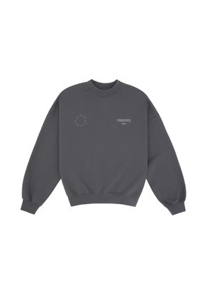 Sweatshirt surdimensionné gris foncé avec logo, jupe mini plissée grise, et bottes noires montantes avec détail de boucle. Modèle portant des lunettes de soleil.