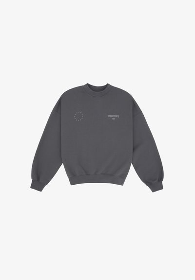 Sweatshirt gris foncé avec un col rond, design à épaule tombante et poignets côtelés. Présente un petit logo circulaire et du texte sur le devant.